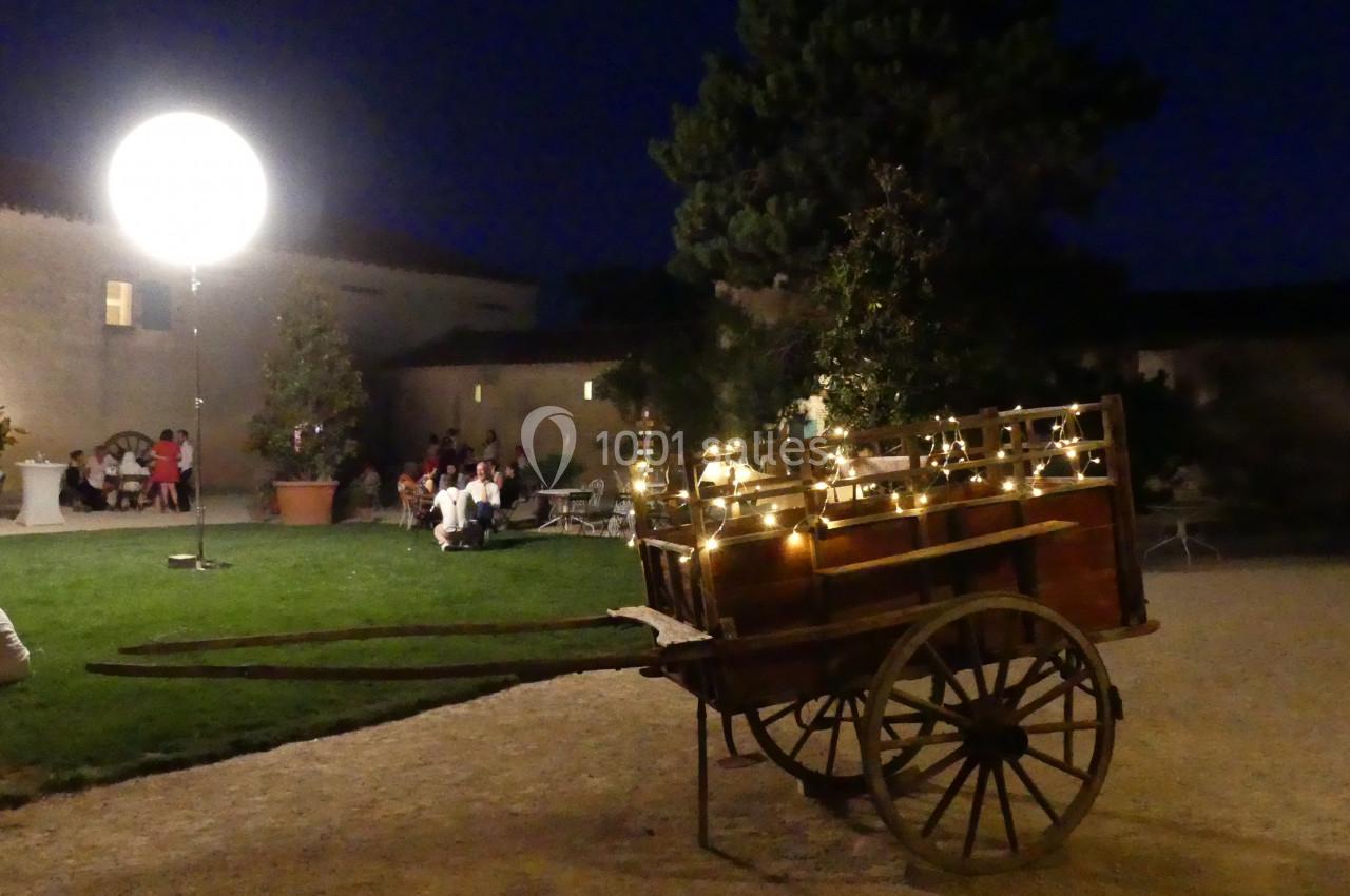 lumières Chariot en bois décoré de guirlandes lumineuses dans une cour éclairée de nuit, avec des personnes en arrière-plan.