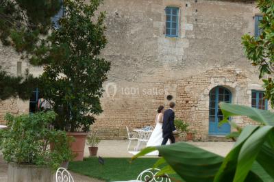 Miniature Vives les mariés ! Un couple marche dans le jardin d'un château ancien entouré de verdure par une journée ensoleillée.
