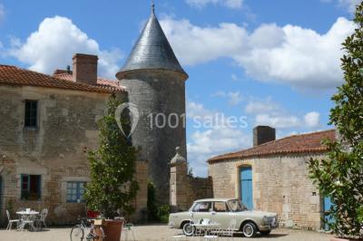 Miniature Voiture des mariés Un couple marche dans le jardin d'un château ancien entouré de verdure par une journée ensoleillée.