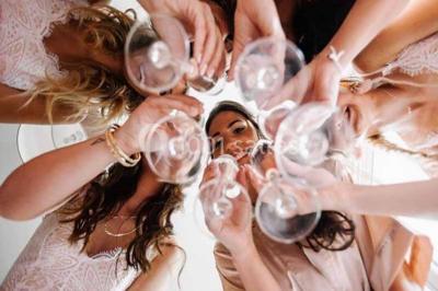 Des femmes en tenue élégante trinquent avec des verres à pied, vues en contre-plongée depuis le centre du cercle.