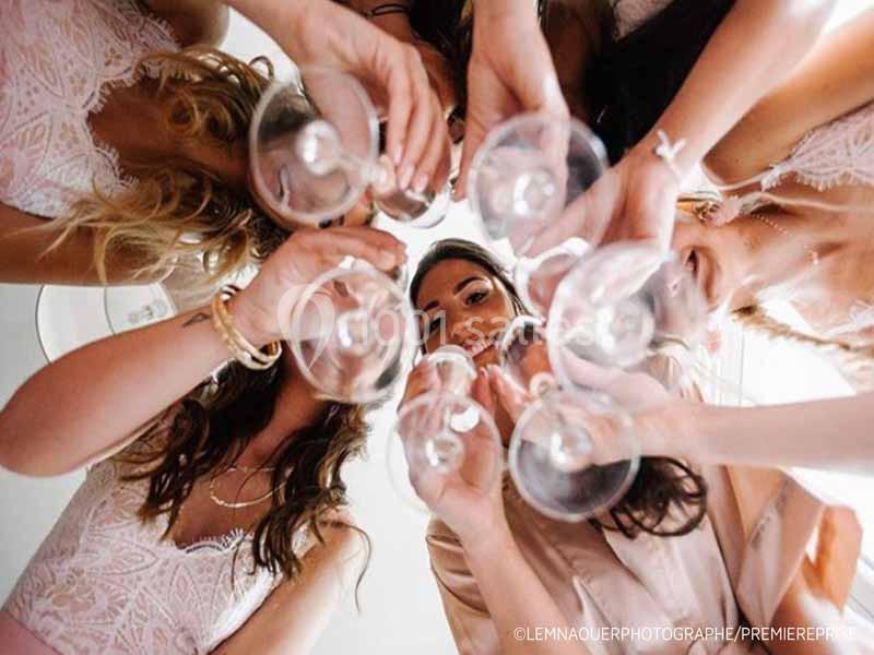 Des femmes en tenue élégante trinquent avec des verres à pied, vues en contre-plongée depuis le centre du cercle.