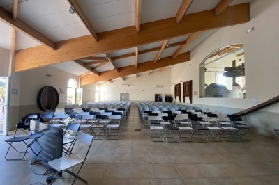 Miniature Location salle Ansouis (Vaucluse) - Le Grand Turcan #3 Salle avec un ancien pressoir en bois, des tonneaux, une table rouge avec bouteilles et des verres à vin.