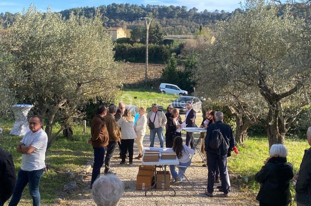 Location salle Ansouis (Vaucluse) - Le Grand Turcan #10 Groupe de personnes rassemblées en plein air dans une oliveraie, discutant autour d'une table avec des documents.
