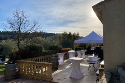 Miniature Location salle Ansouis (Vaucluse) - Le Grand Turcan #4 Salle avec un ancien pressoir en bois, des tonneaux, une table rouge avec bouteilles et des verres à vin.