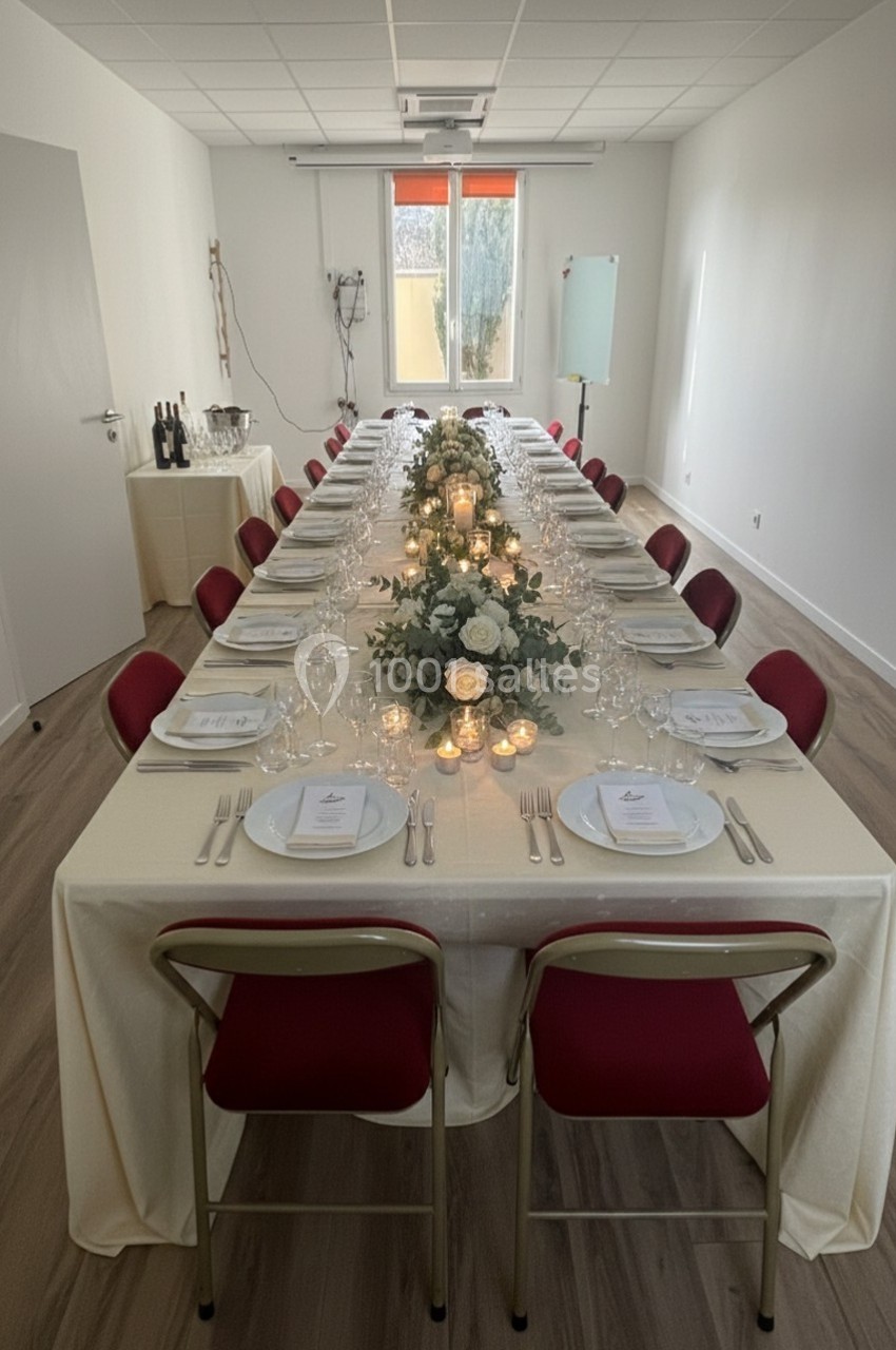 Table dressée pour un repas formel, avec nappes blanches, vaisselle élégante, bougies et décoration florale.