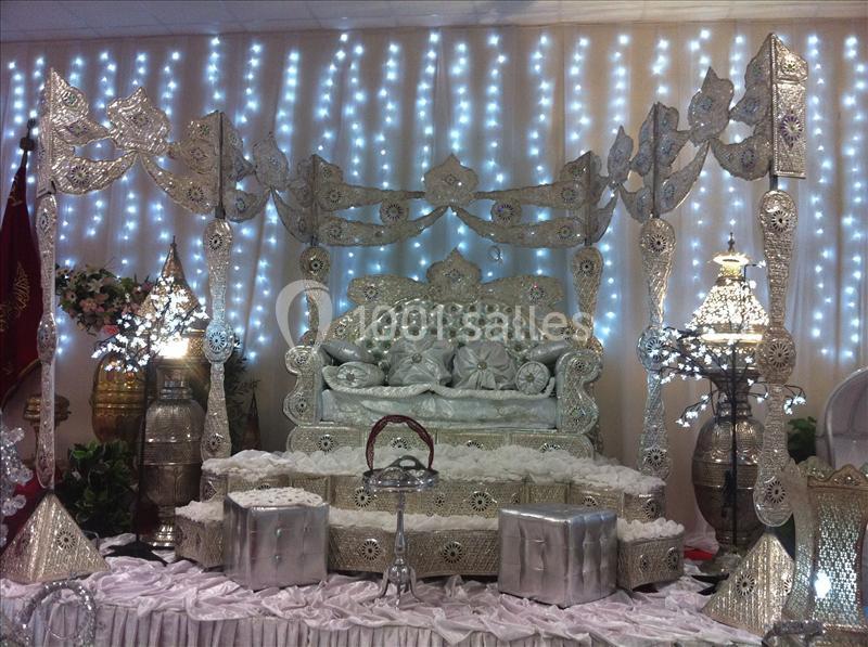 Décorations traditionnelles argentées avec un trône orné, des motifs détaillés et des lumières en arrière-plan.