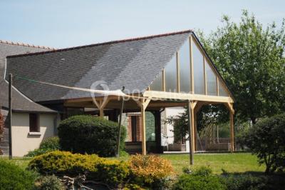 Un couple en tenue de mariage se regarde sous une pergola illuminée de guirlandes lumineuses.