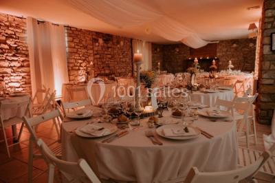 Un couple en tenue de mariage se regarde sous une pergola illuminée de guirlandes lumineuses.