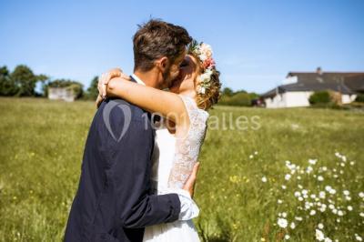 Un couple en tenue de mariage se regarde sous une pergola illuminée de guirlandes lumineuses.