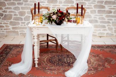 Un couple en tenue de mariage se regarde sous une pergola illuminée de guirlandes lumineuses.