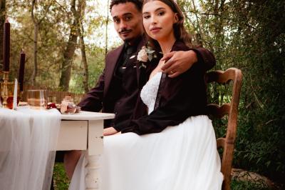 Un couple en tenue de mariage se regarde sous une pergola illuminée de guirlandes lumineuses.