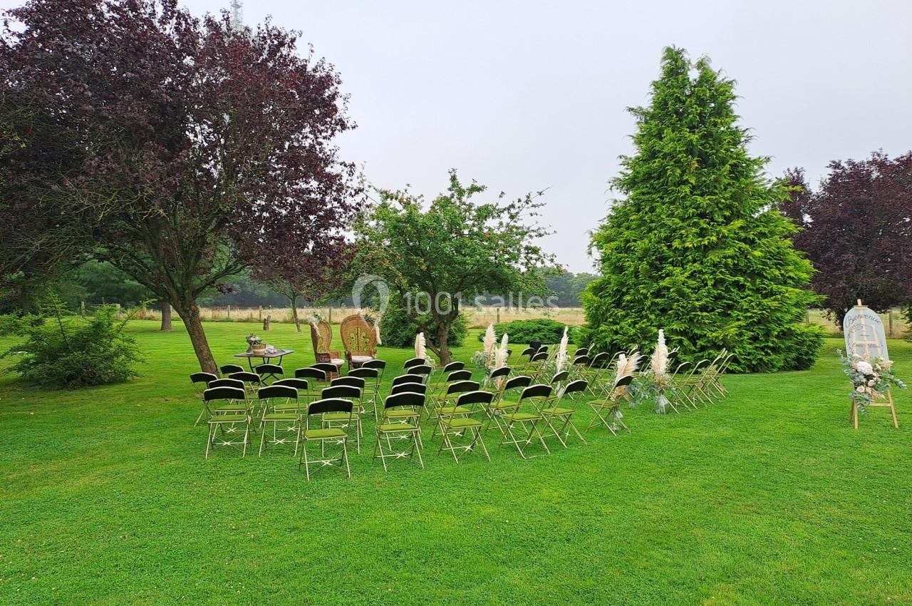Chaises alignées en extérieur sur une pelouse, entourées d'arbres, préparées pour un événement en plein air.