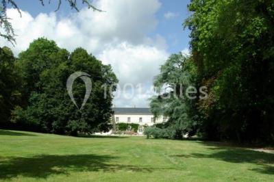Chambre lumineuse avec un lit double, des rideaux fleuris, un lustre, des meubles classiques et des fenêtres donnant sur la…