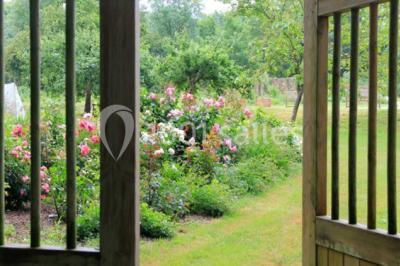 Chambre lumineuse avec un lit double, des rideaux fleuris, un lustre, des meubles classiques et des fenêtres donnant sur la…