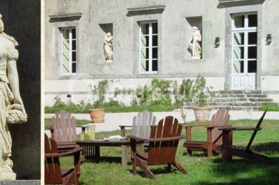 Chambre lumineuse avec un lit double, des rideaux fleuris, un lustre, des meubles classiques et des fenêtres donnant sur la…