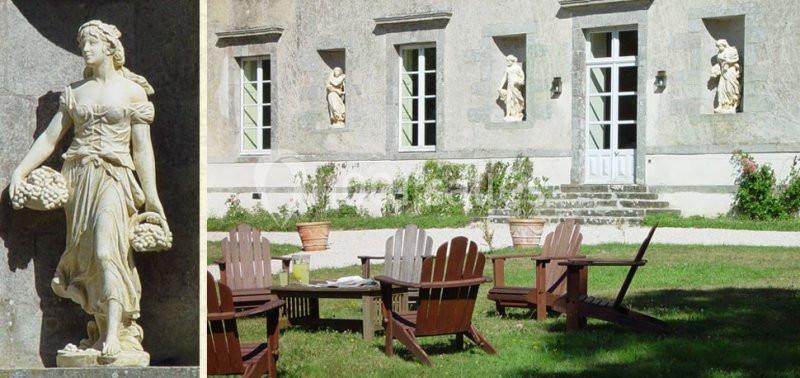 Statue classique et chaises en bois disposées sur une pelouse devant une façade en pierre avec fenêtres et sculptures.